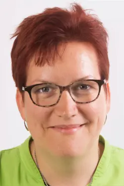 Portretfoto van Isabelle De Cock, tandartsassistente, met kort rood haar en bril.